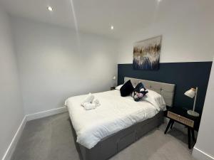 une chambre avec un grand lit avec des draps et des oreillers blancs dans l'établissement The Fortis Apartments - 1 Bed - WIFI - Videocom Entry - Close to Bus & Train Stations - Professionals, Contractors & Tourist Ready, à Peterborough