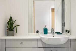 a white bathroom with a sink and a mirror at Modern City Centre Apartment in Bradford in Bradford