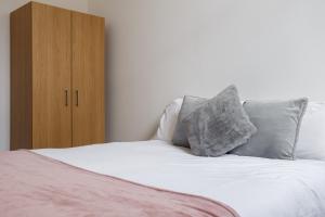 a bed with two pillows and a wooden cabinet at Modern City Centre Apartment in Bradford in Bradford