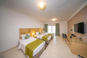 a hotel room with two beds and a flat screen tv at City Stay Prime Hotel Apartments - Al Barsha in Dubai +59 photos