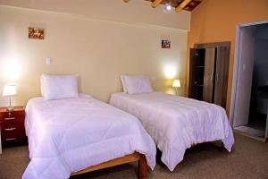2 camas en un dormitorio con sábanas y almohadas blancas en Veronica lookout Hotel, en Urubamba 5 fotos más