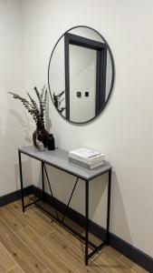 a table with a mirror on a wall at Luxury Apartment Close to Elstree & Borehamwood Station in Borehamwood