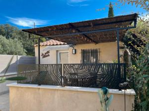 una recinzione davanti a una casa con un pergolato di La Petite Maison a Bédoin