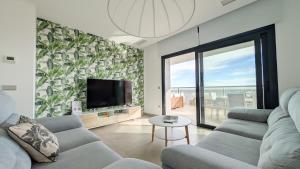 ein Wohnzimmer mit Sofa und Fernseher in der Unterkunft SUNSET CLIFFS azure apartment in Benidorm