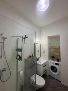 a bathroom with a shower toilet and a washing machine at Apartament Noniewicza 95 in Suwałki +3 photos