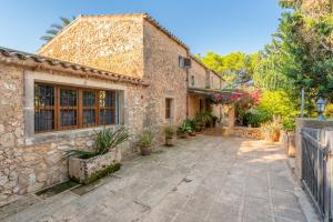 a stone house with a courtyard and a fence at Finca Can Quadrat by Mallorca House Rent in Caʼs Concos