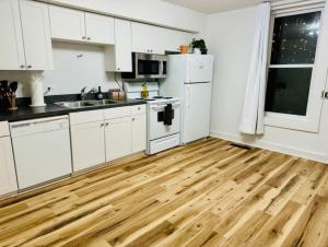 a kitchen with white cabinets and a wooden floor at Short North Convention King Bed Free Parking! in Columbus