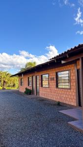 a brick house with a gravel driveway in front of it at Chalés Paraíso das Ilhas - Alto Cedros. in Rio dos Cedros