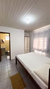 a large white bed in a room with a window at Chalés Paraíso das Ilhas - Alto Cedros. in Rio dos Cedros