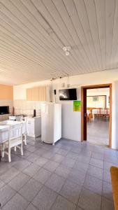 a kitchen with white appliances and a table and chairs at Chalés Paraíso das Ilhas - Alto Cedros. in Rio dos Cedros