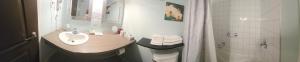 a white bathroom with a sink and a shower at Petit Hôtel Amara in La Malbaie