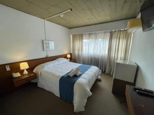 a hotel room with a bed and a television at Hotel Los Pinos Punta in Punta del Este