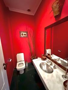 a red bathroom with a sink and a toilet at Casa divina in Yerba Buena