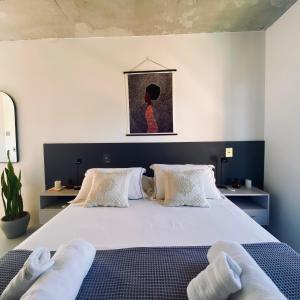 um quarto com uma cama grande com lençóis brancos e um quadro em Apartamento moderno no MaxHaus Praia Brava Piscinas, Academia e Vista Verde em Itajaí mais 31 fotografias
