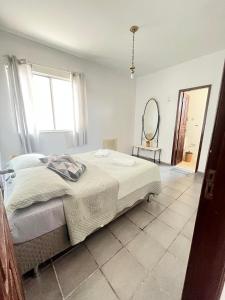 a white bedroom with a bed and a mirror at COP 30, Mosqueiro - Apto pé na areia in Belém