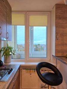 une cuisine avec une chaise noire devant deux fenêtres dans l'établissement 8th floor panorama studio in Klaipėda - self check in, à Klaipėda