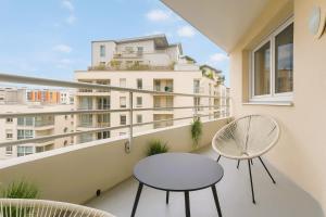 a balcony with two chairs and a table and a building at MyCityHaven Paris La Défense in Courbevoie