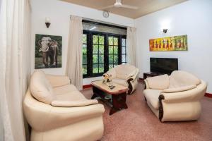 ein Wohnzimmer mit zwei Stühlen und einem Tisch und einem Fernseher in der Unterkunft Omni Holiday Bungalow in Mount Lavinia