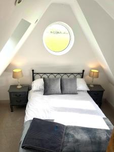 Schlafzimmer mit einem großen Bett und einem runden Fenster in der Unterkunft The Stables, a delightful 3 bed house near the Norfolk Broads in Upton
