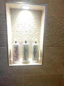 zwei weiße Flaschen mit Duftstoffen in einer Nische im Badezimmer in der Unterkunft The Stables, a delightful 3 bed house near the Norfolk Broads in Upton