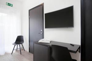 a room with a desk with a television on a wall at Nordurey Hotel City Garden in Reykjavík