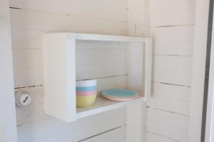 The Vintage La Mesa Tudor في Spring Valley: خزانة بيضاء بها أوعية وأطباق على رف