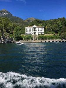 a boat in a body of water with a building at Una terrazza sul lago in Argegno