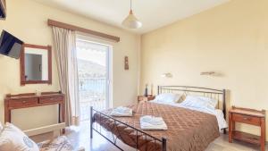 a bedroom with a bed and a large window at Akrotopi Apartments & Studios in Tolo