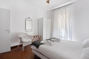 a white bedroom with a bed and a chair at Maison18 in Pegazzano