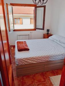 a small bedroom with a bed with a window at Chalet adosado entre playas in Argoños