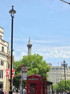 a red phone booth on a city street with a tower at Original Trafalgar Square Apartment near Buckingham Palace in London
