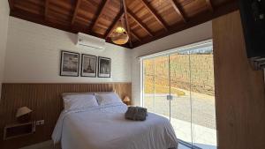 una camera da letto con un letto e una grande finestra di Rancho Ipês do Lago a Socorro Altre 287 foto
