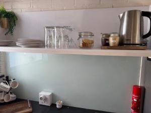 a shelf with jars and plates and a coffee pot at Eagles Rest Guest House in Summerstrand