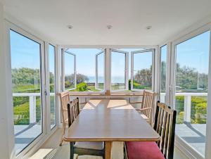ein Esszimmer mit Tisch und Stühlen und Fenstern in der Unterkunft The Owl - Felpham in Middleton-on-Sea