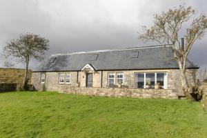 a stone house on a hill with a green field at The Bothy at Redheugh in Newcastleton