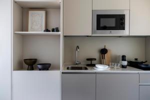 a kitchen with white cabinets and a microwave at Calido Las Tablas in Madrid