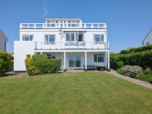 ein weißes Haus mit einem Rasen davor in der Unterkunft The Owl - Felpham in Middleton-on-Sea