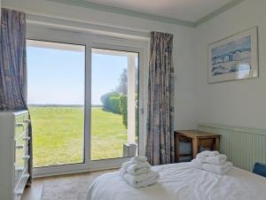 ein Schlafzimmer mit einem Bett und einem großen Fenster in der Unterkunft The Owl - Felpham in Middleton-on-Sea