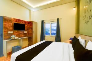 ein Hotelzimmer mit einem Bett und einem Fernseher in der Unterkunft Hotel O Palm Inn Durgapura Railway Station in Jaipur + 23 Fotos