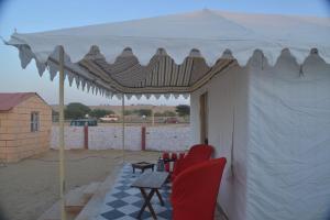 a white tent with red chairs and a table at Kesariya Heritage Resorts in Jaisalmer