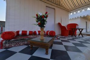 a living room with a couch and a vase with flowers on a table at Kesariya Heritage Resorts in Jaisalmer