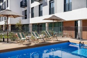 a pool with chairs and umbrellas next to a building at Calido Las Tablas in Madrid
