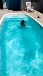 una persona nadando en una gran piscina azul en Casa Com Piscina - Mongaguá - Disponível Feriado Carnaval, en Mongaguá