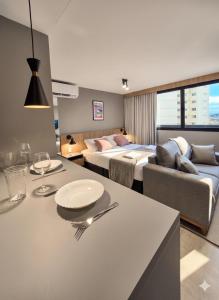 a room with two beds and a living room with a table at A7 Vix by Housi – studios e apartamentos modernos em Vitória in Guajuru