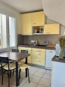 a kitchen with yellow cabinets and a table and chairs at L'Air Marin in Barbâtre