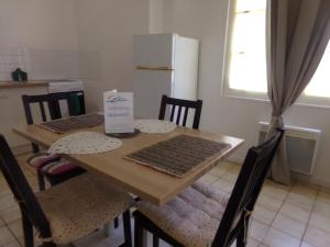 a kitchen with a table with chairs and a refrigerator at Le Goéland in Dieppe