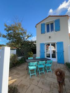 a dog standing next to a table and chairs at L'Air Marin in Barbâtre