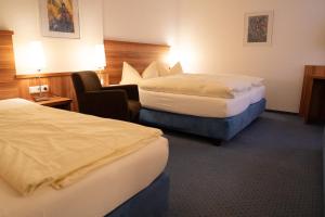 a hotel room with two beds and a chair at Hotel Jägerhof in Bad Hersfeld