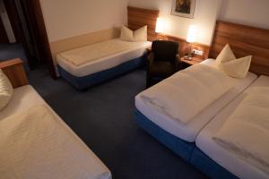 a hotel room with two beds and a chair at Hotel Jägerhof in Bad Hersfeld