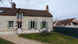 a house with green shutters and a table in the yard at Longère chez Martine et Julie in Romorantin
